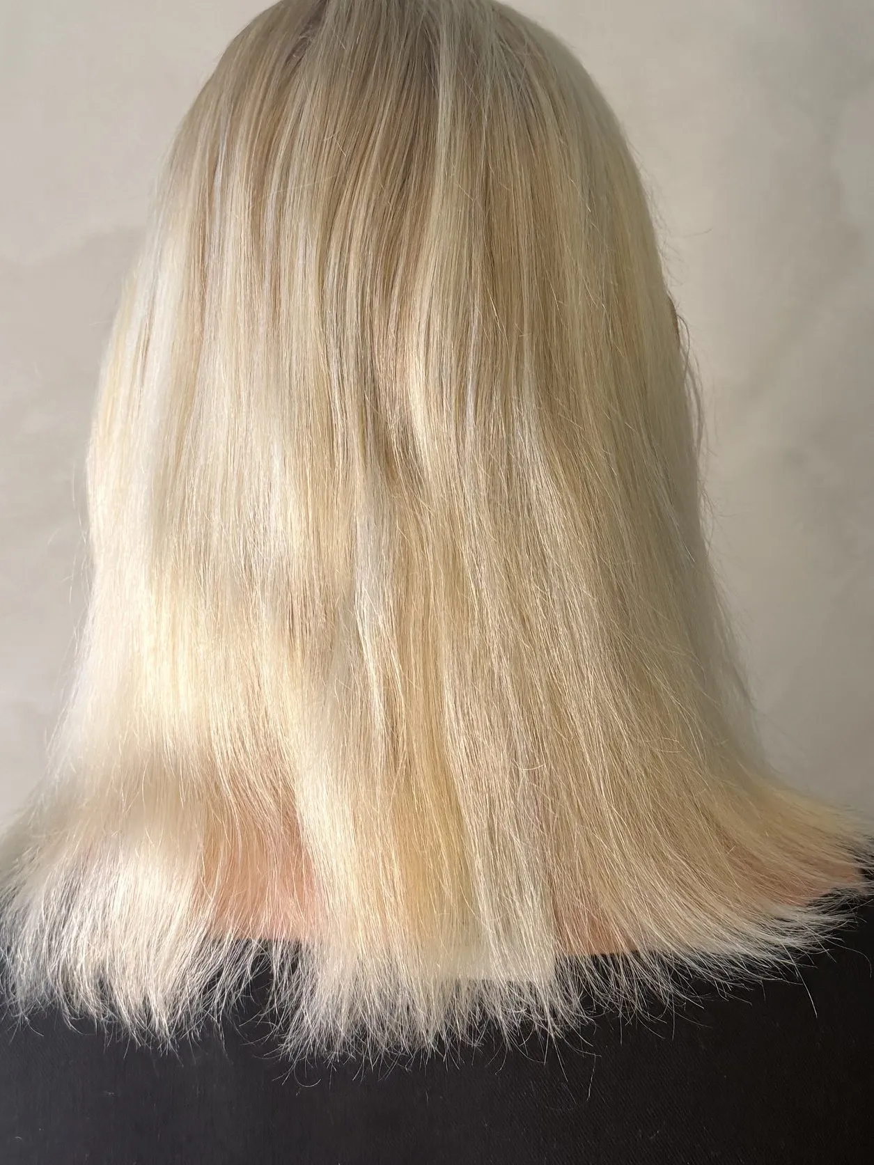 Blondt hår til skulderen, tynt i tuppene, sett bakfra