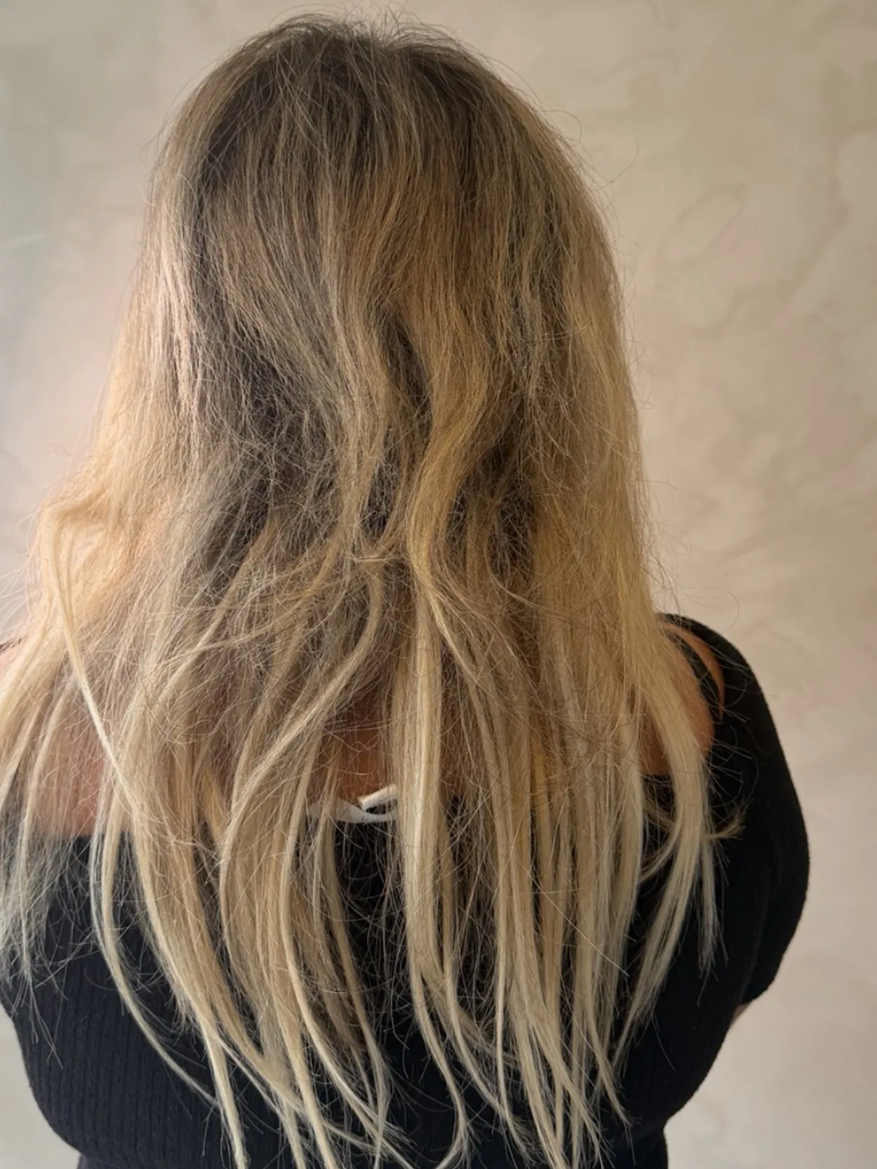 Langt, tynt og slitt blondt hår sett bakfra